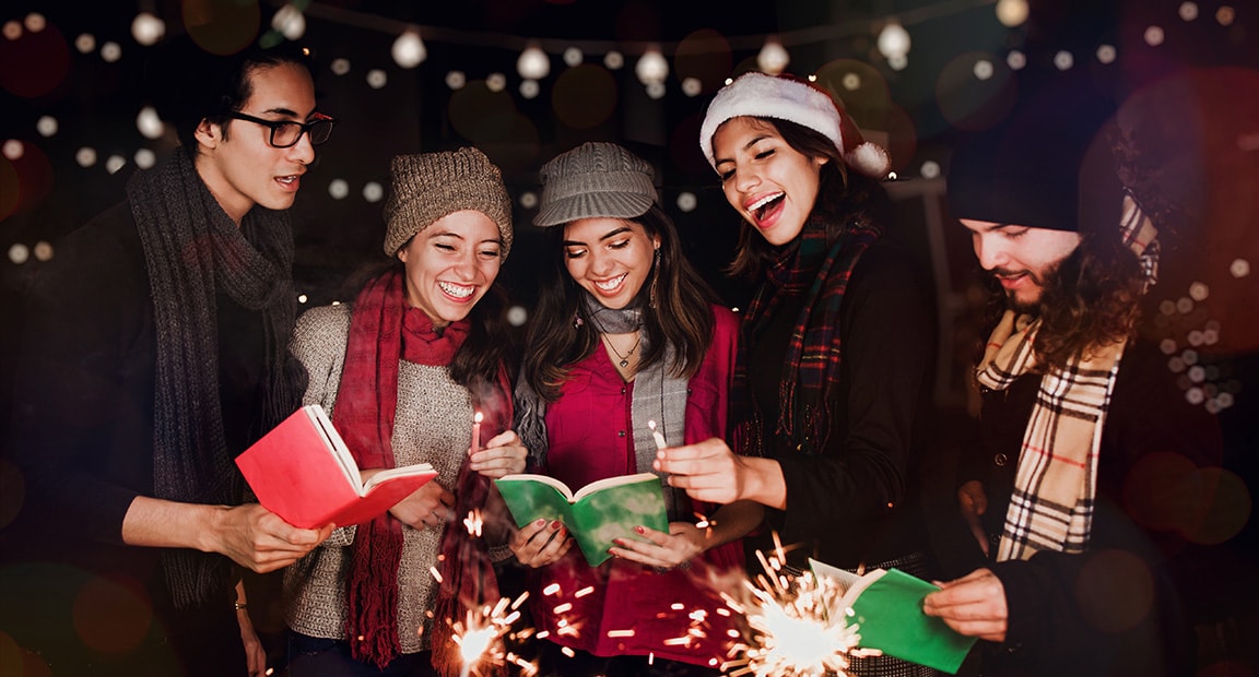 4 christmas carolers bundled up and singing