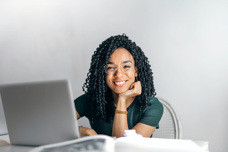 girl sitting at desk with laptop smiling