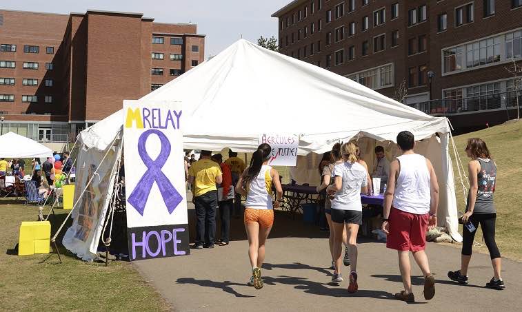 college students in running gear entering a large canvas tent to register for an Alzheimer's fundraising relay race