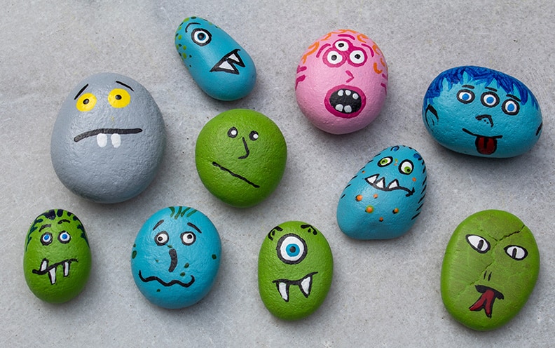9 small rocks that have been painted with funny faces on them