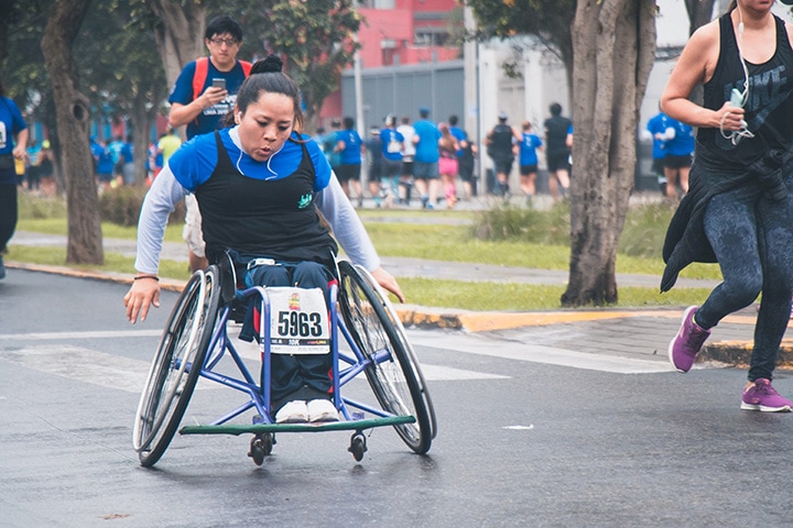 woman in wheelchair racing with runners in a charity competition