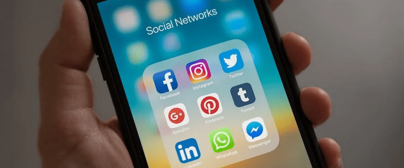 hand holding cell phone with social media icons on screen