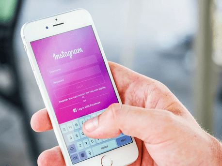 right hand holding smart phone with tumb opening instagram