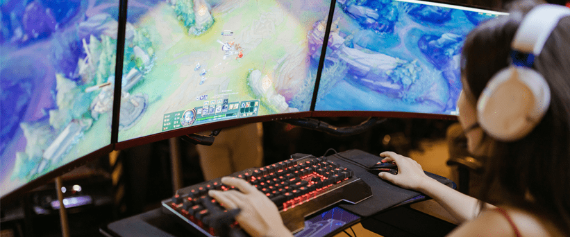 woman gaming using three monitors sitting at desk