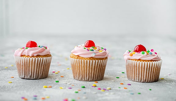 3 frosted cupcakes with sprinkles in a row