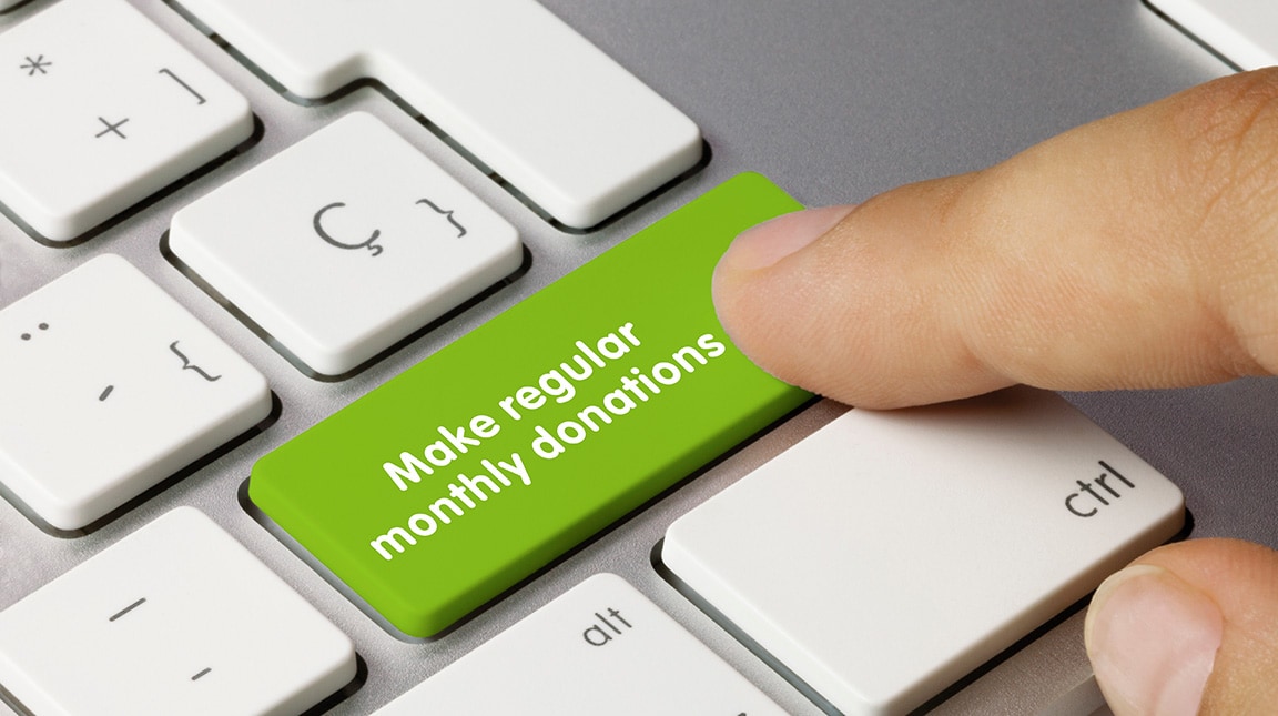 Make regular monthly donations Written on Green Key of Metallic Keyboard. Finger pressing key.