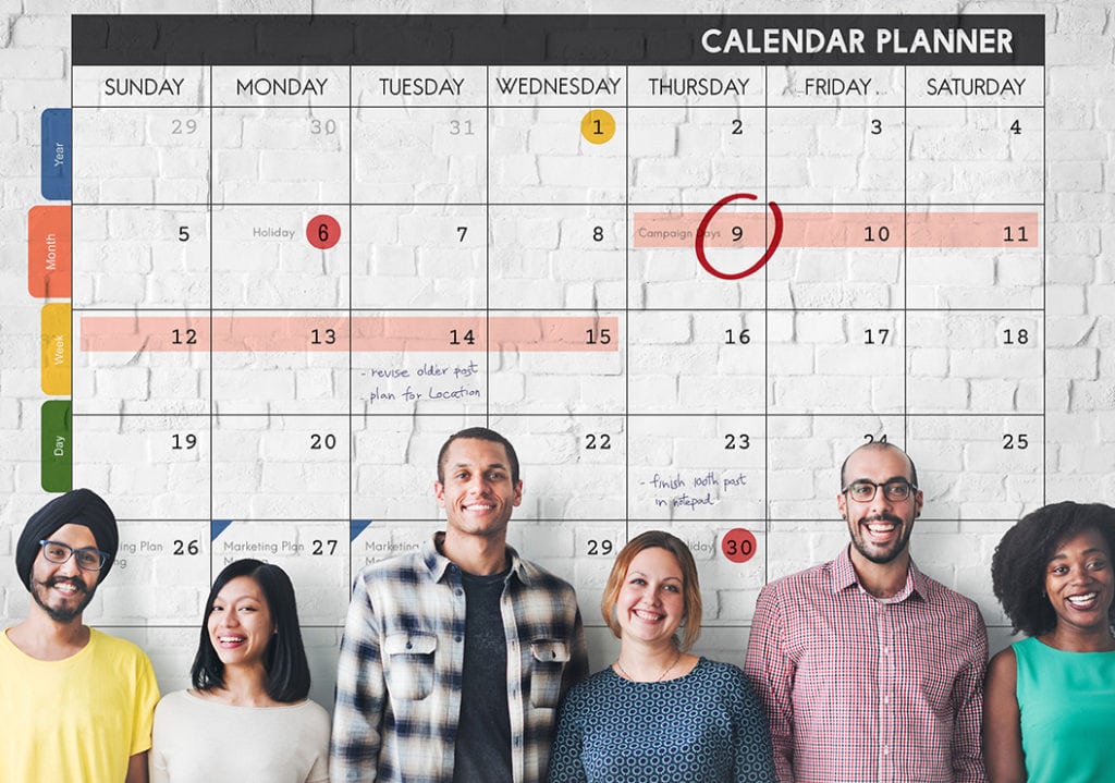 5 committee members standing in front of giant calendar
