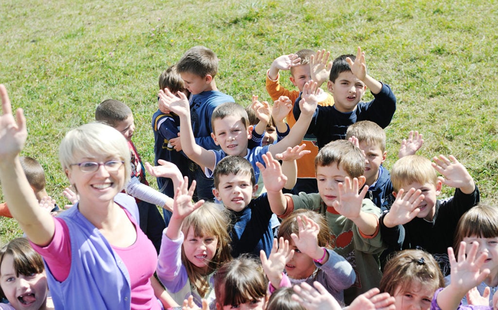 young students with teacher outside on nice day