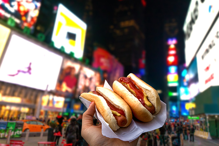 Holding two hot dogs in NYC on the Times Square .