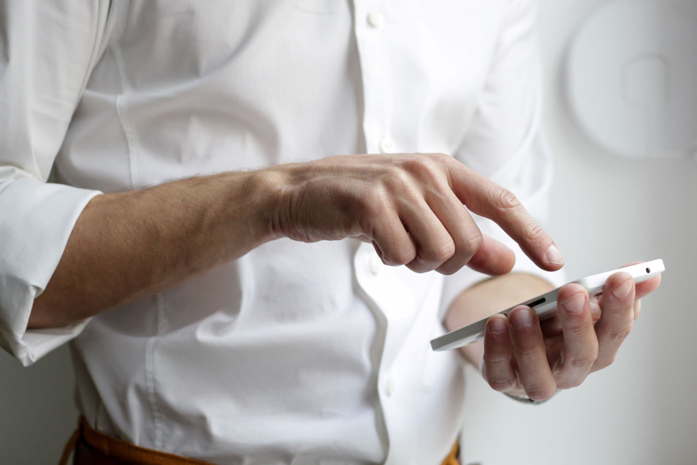 Man in a button-down holding a smartphone