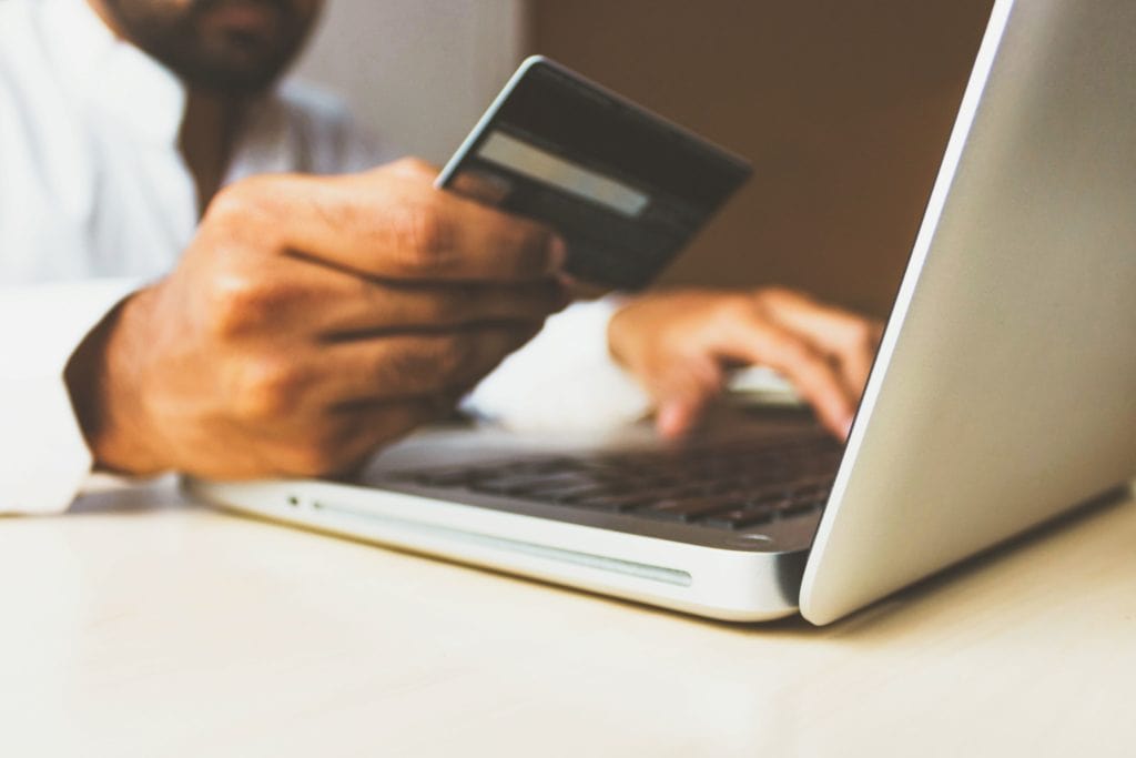 hand holding a credit card over laptop