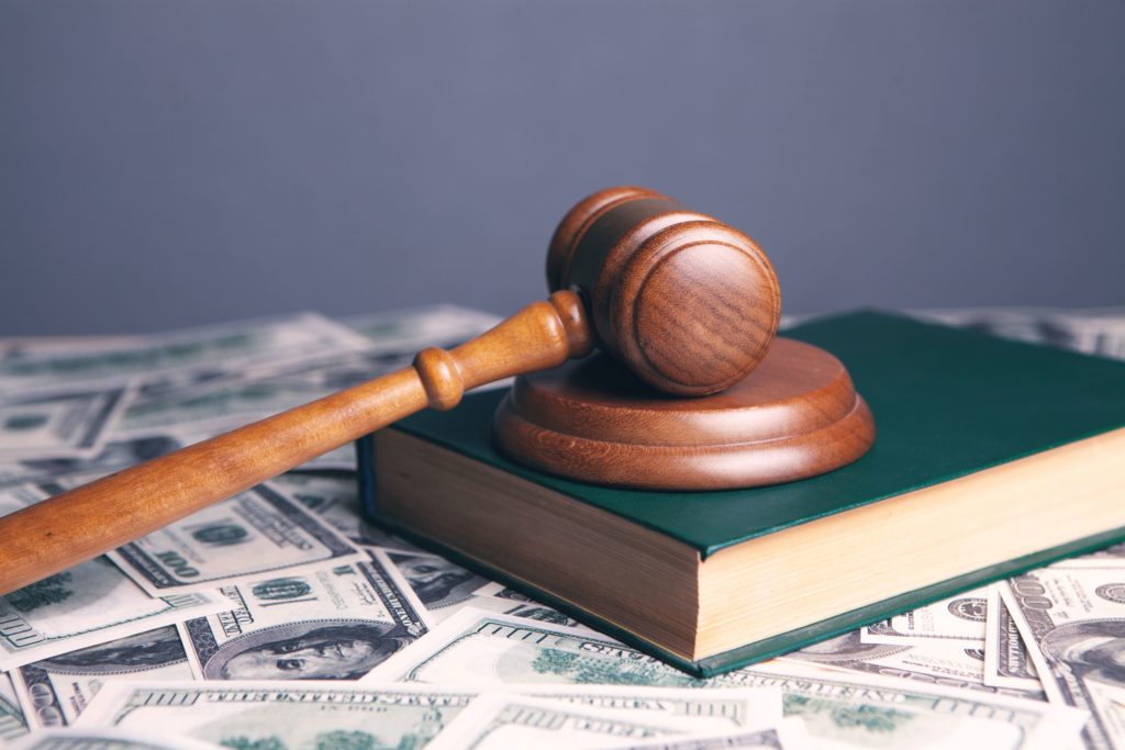 gavel resting on a book on top of a bed of cash