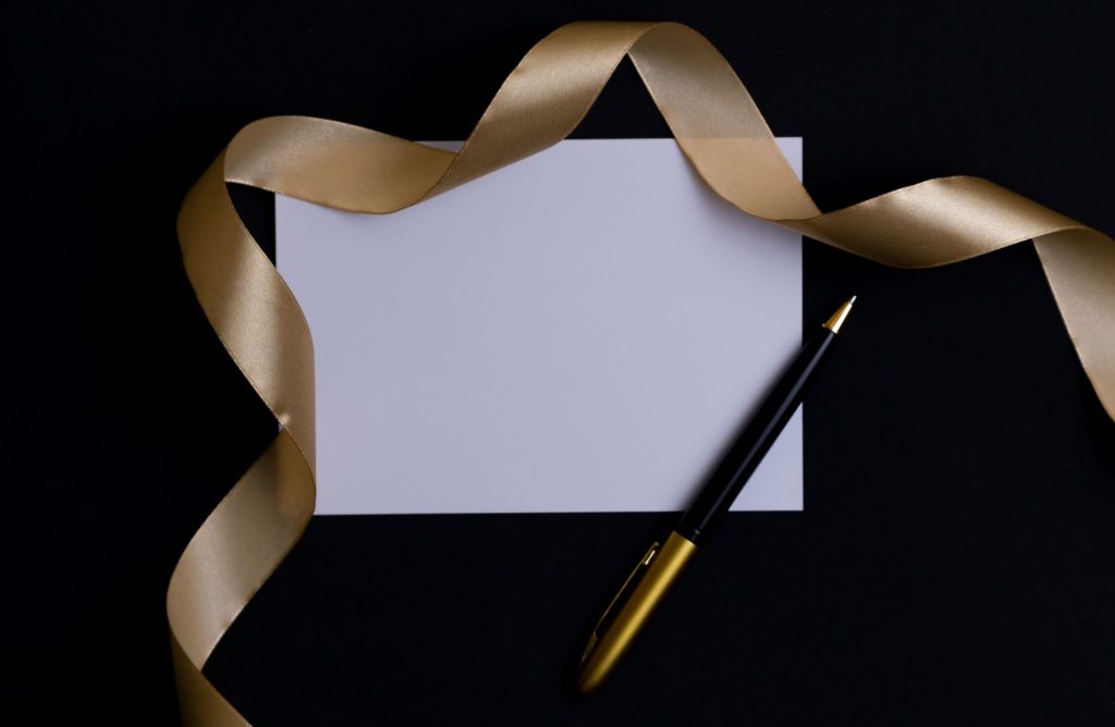blank invitation with gold ribbon and pen