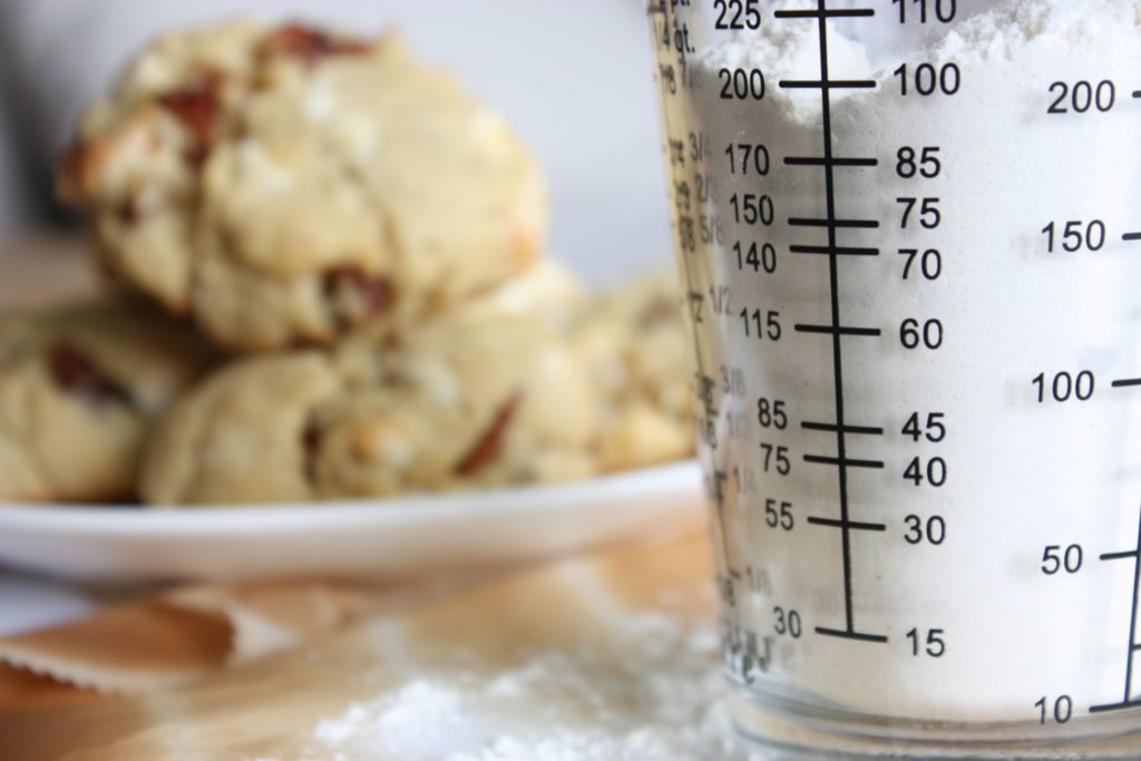 flour in a measuring cup and cookies on a plate