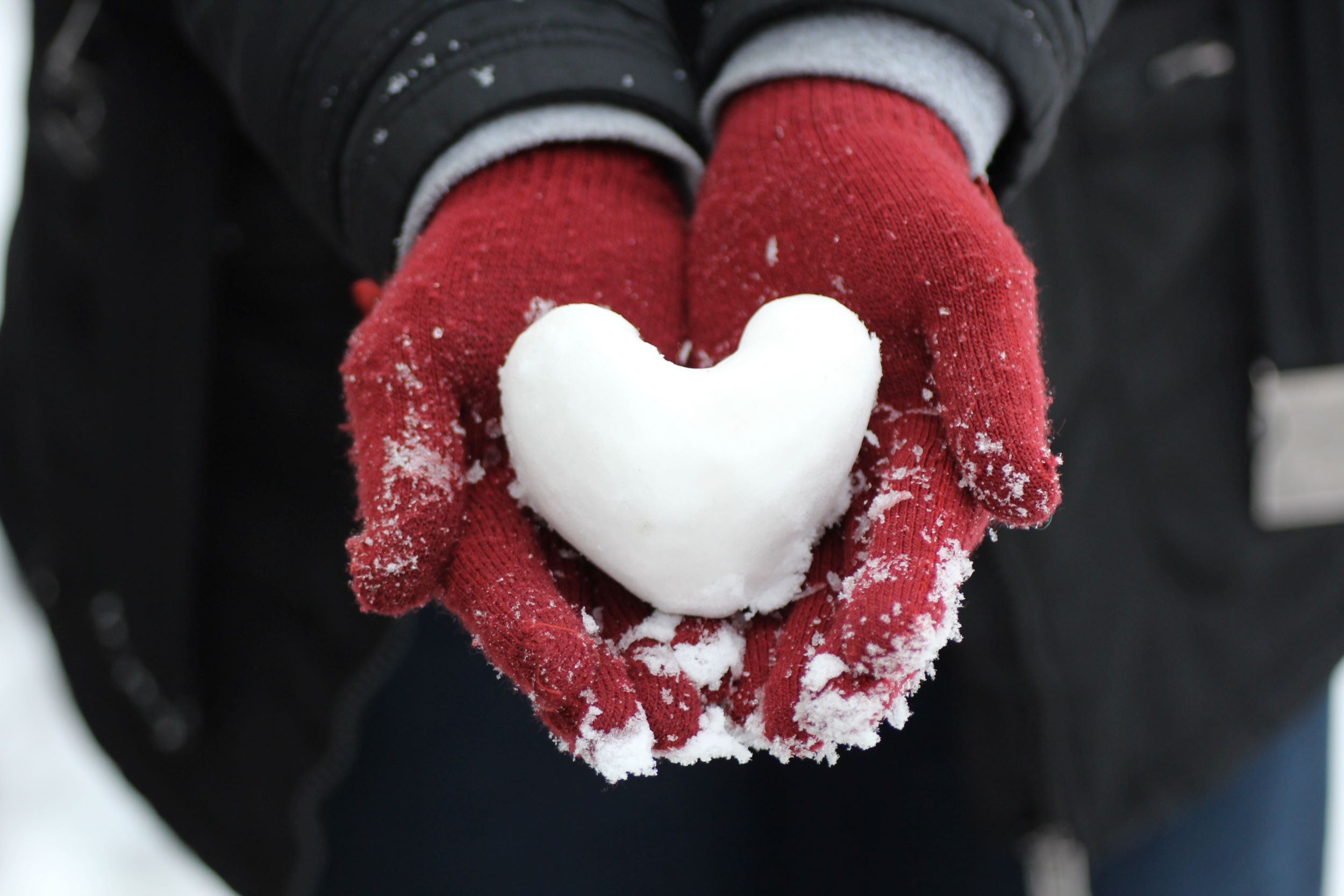 mittened hands offering snow heart