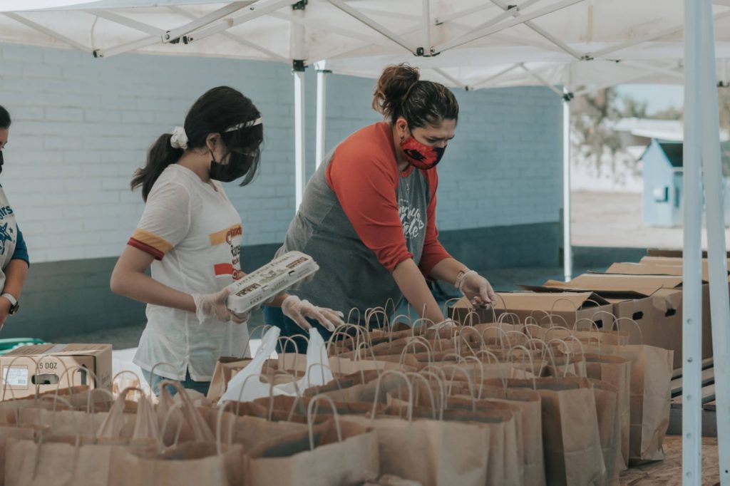 volunteers filling paper bags at food drive