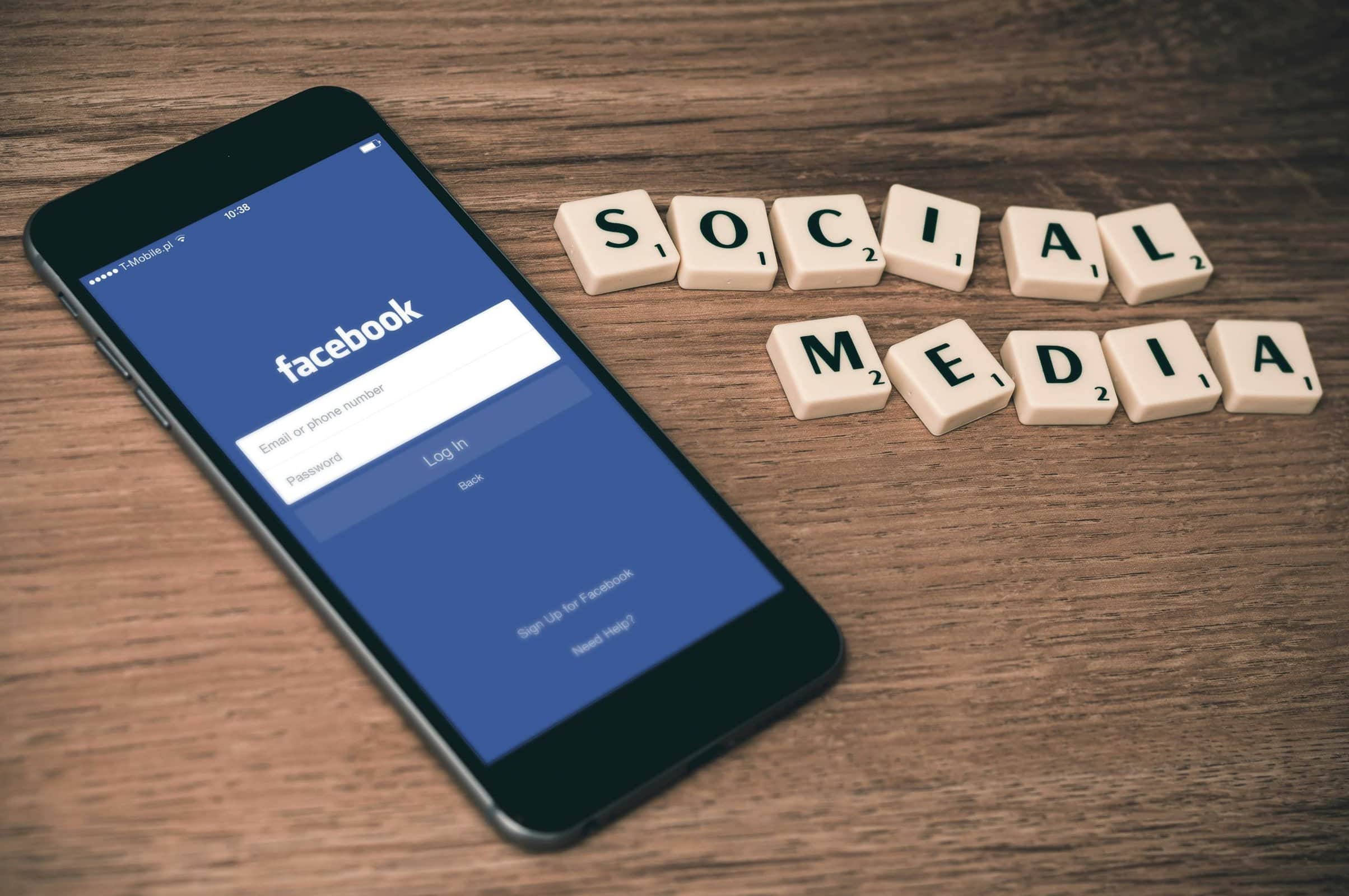 phone with facebook login page pulled up and scrabble tiles that spell "social media"