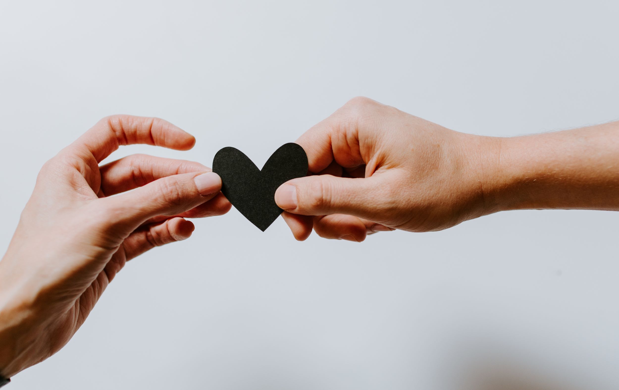 photo of two hands holding a paper heart