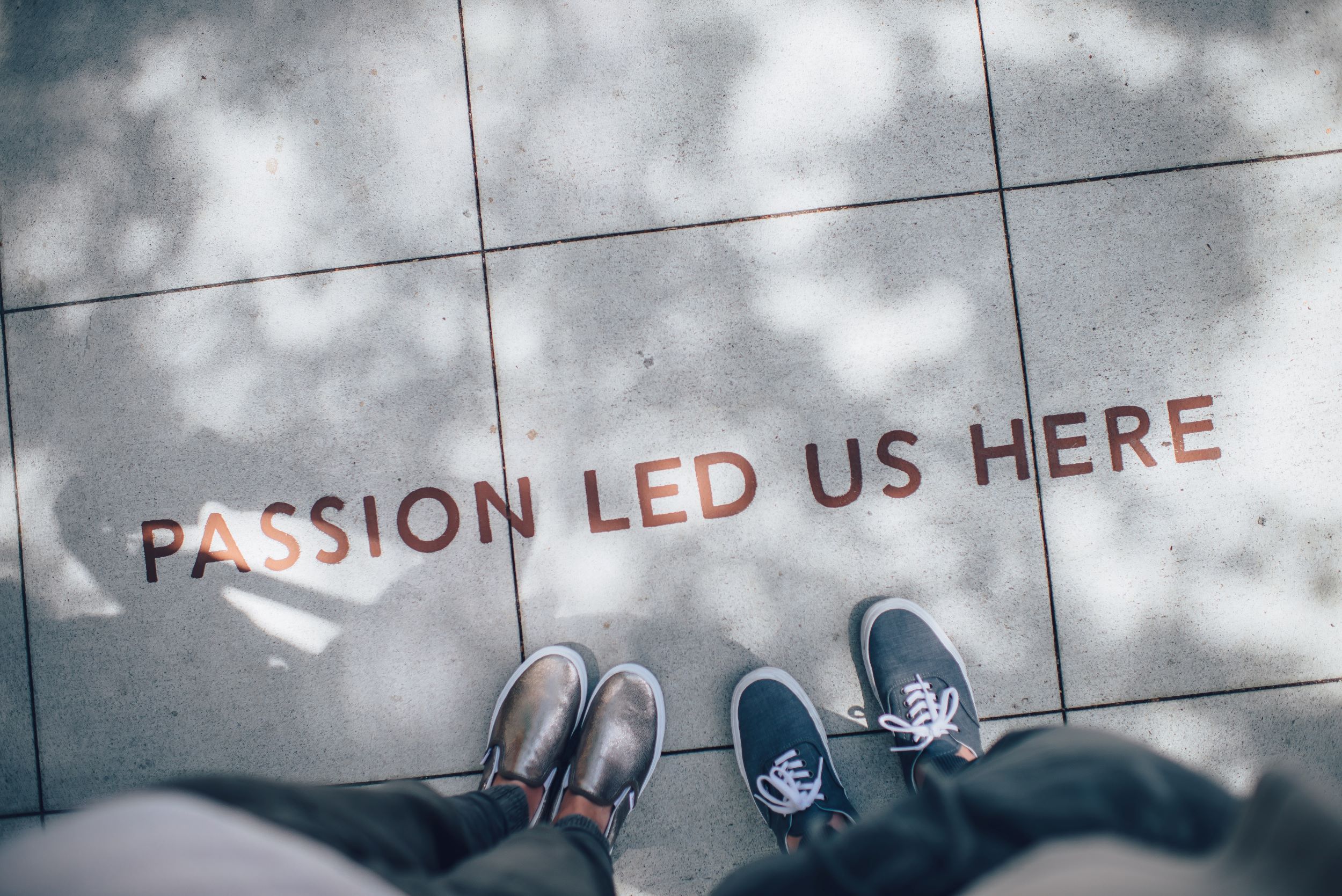 photo of sidewalk art that says "passion led us here" with two people's feet