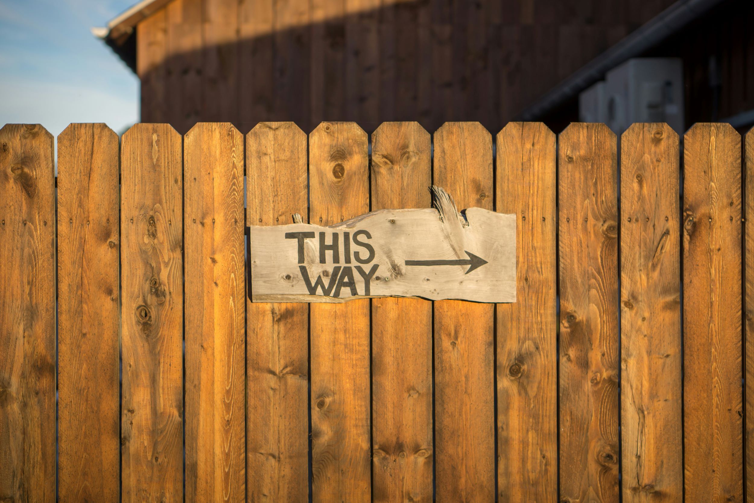 fence with sign that says "this way"