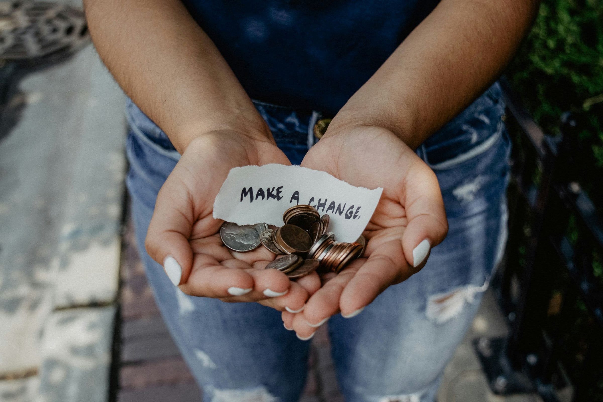 hands holidng loose change and a note that says "make a change"