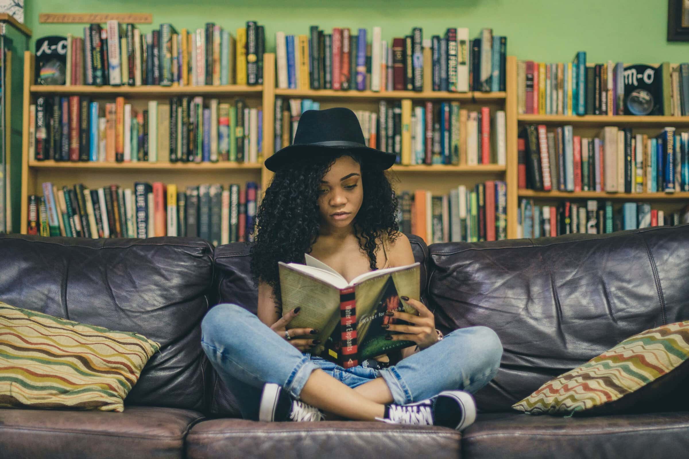 woman seated reading in front of bookshelves