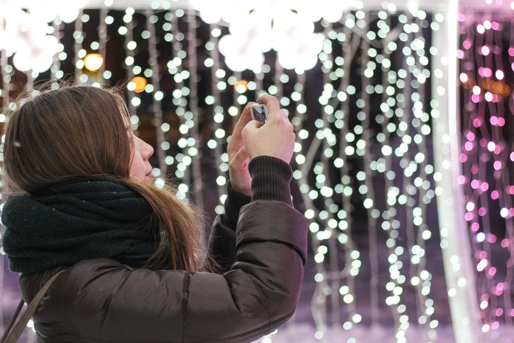 girl taking picture of holiday lights